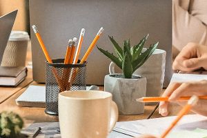 Belistifte im Halter, Kaktus im Topf, Kaffeetasse und Hände mit Bleistifte