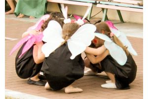 5 Kinder in Schmetterlingskostümen sind in hockender Position zueinander gedreht.