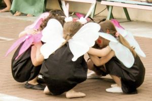 5 Kinder in Schmetterlingskostümen sind in hockender Position zueinander gedreht.