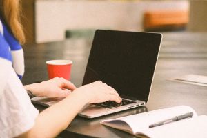 Aufgeschlagener Lap-Top mit Frau die darauf arbeitet