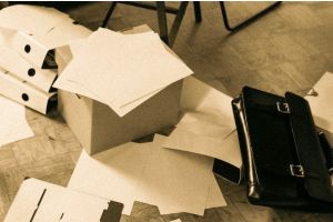 Chaotische Papierblätter liegen auf Schachteln und auf dem Boden